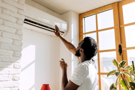 man turning on air conditioner at home