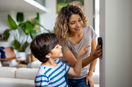 Mother and son at home using a smart thermostat.